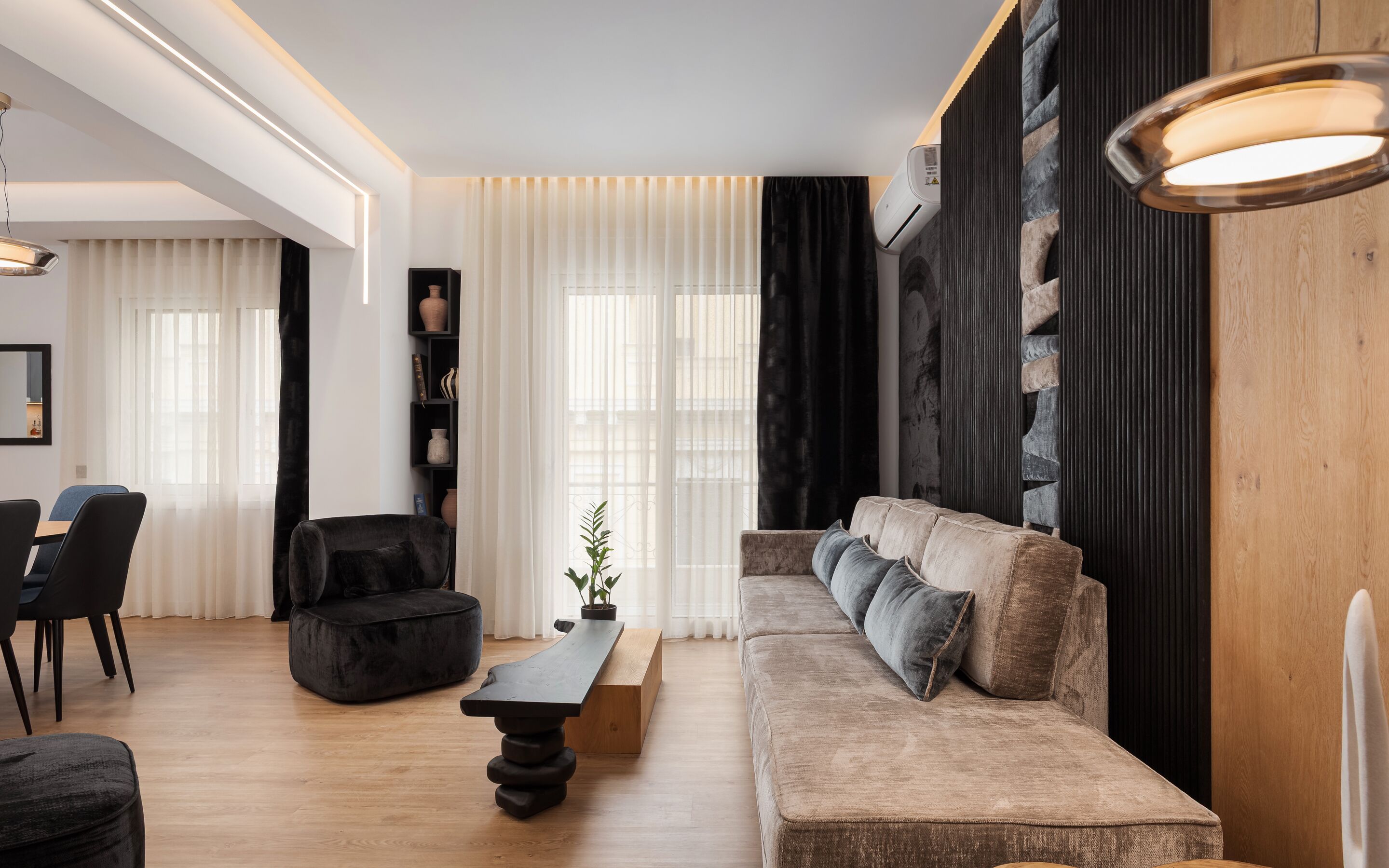 A modern living room with a sofa, chairs, a coffee table, and a potted plant.