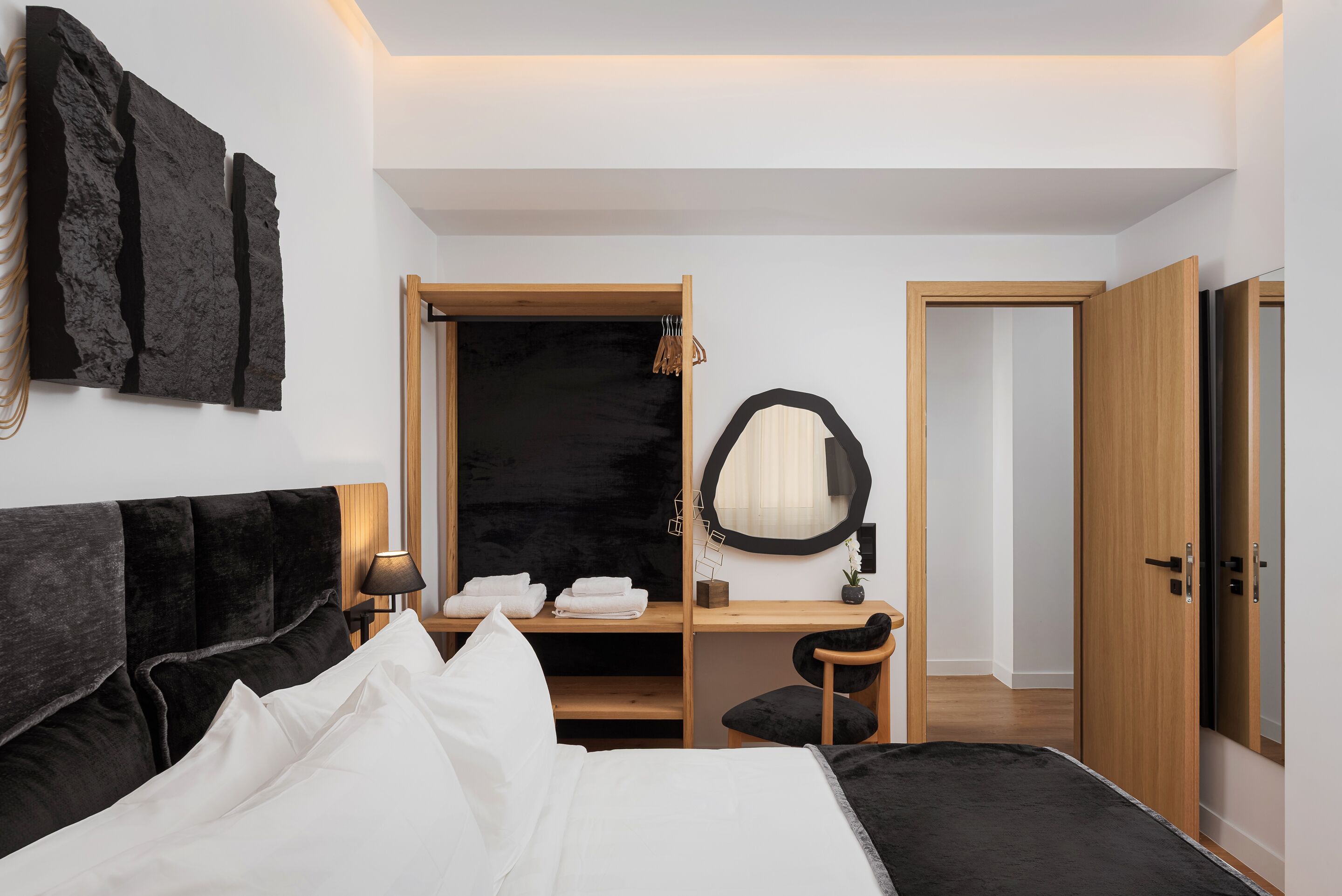 A modern bedroom with a bed, a desk, a chair, a wardrobe, and a mirror.