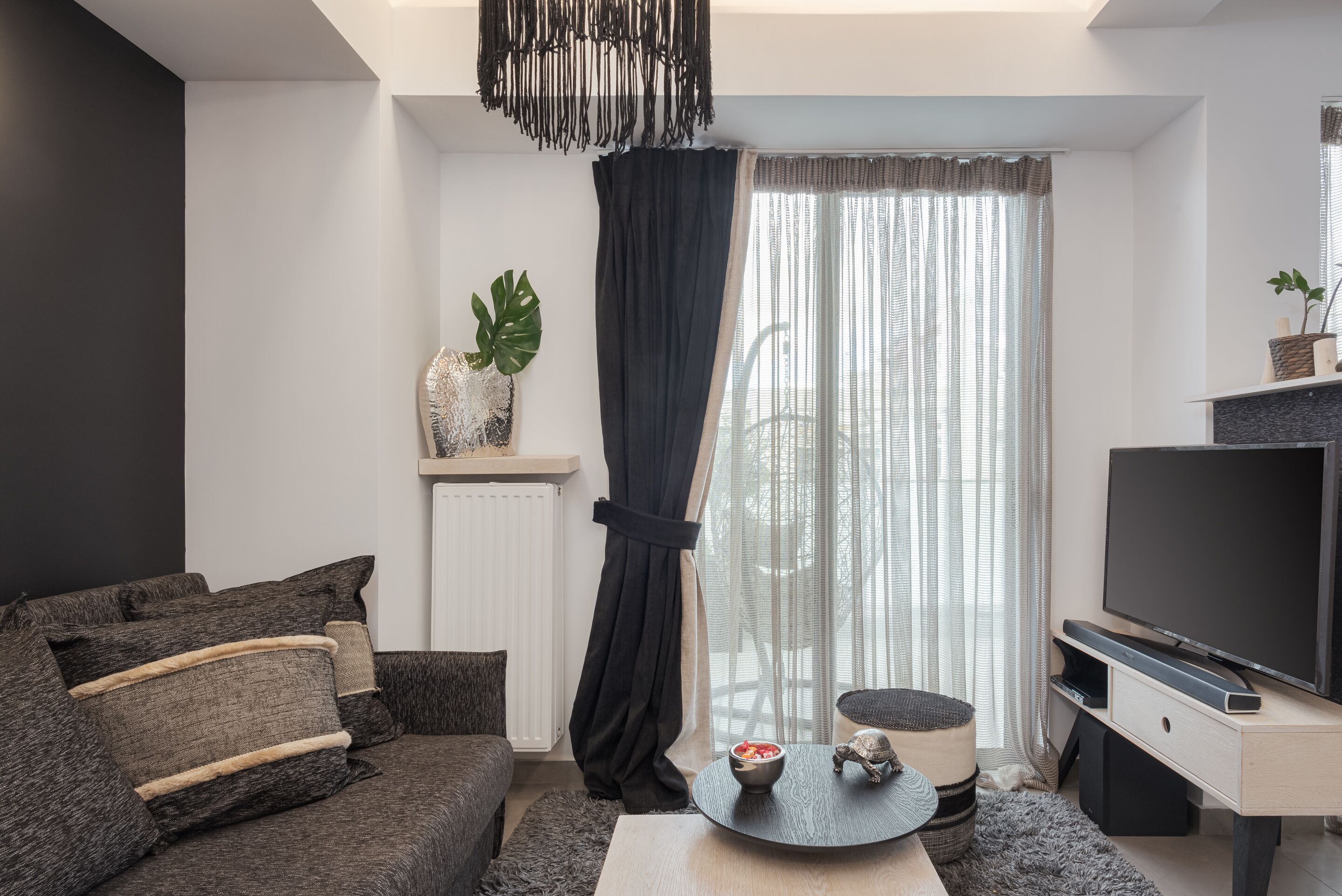A modern living room with a dark-colored sofa, a round coffee table, and a flat-screen TV on a wooden stand.