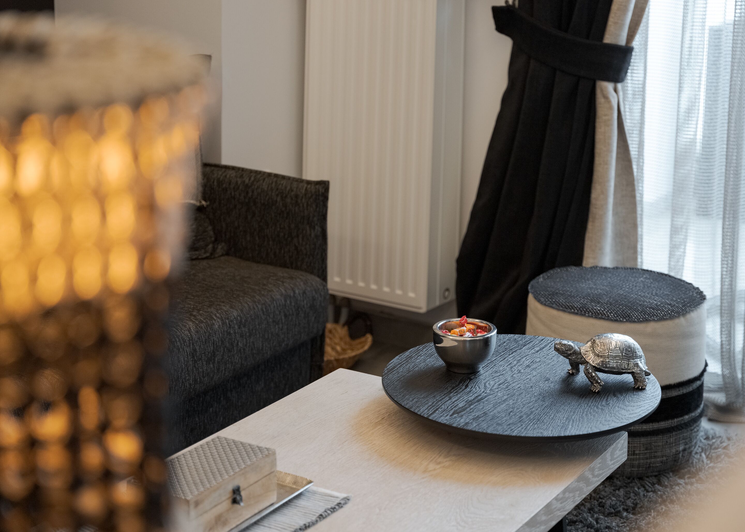 A cozy living room with a sofa, a small table with a bowl of snacks, a decorative turtle, and a lamp.