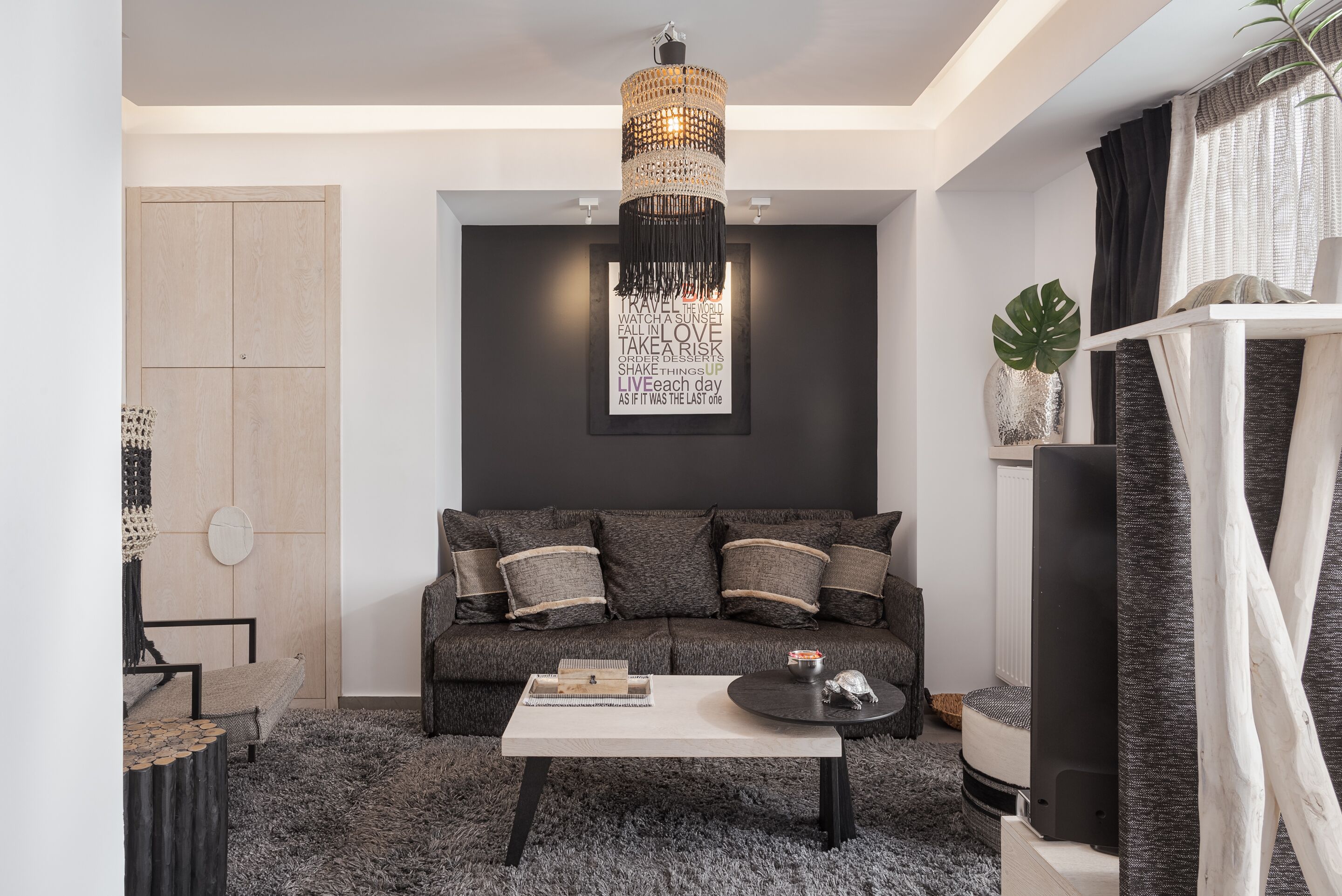 Un salon moderne avec un canapé gris, une table basse blanche et un lustre décoratif.