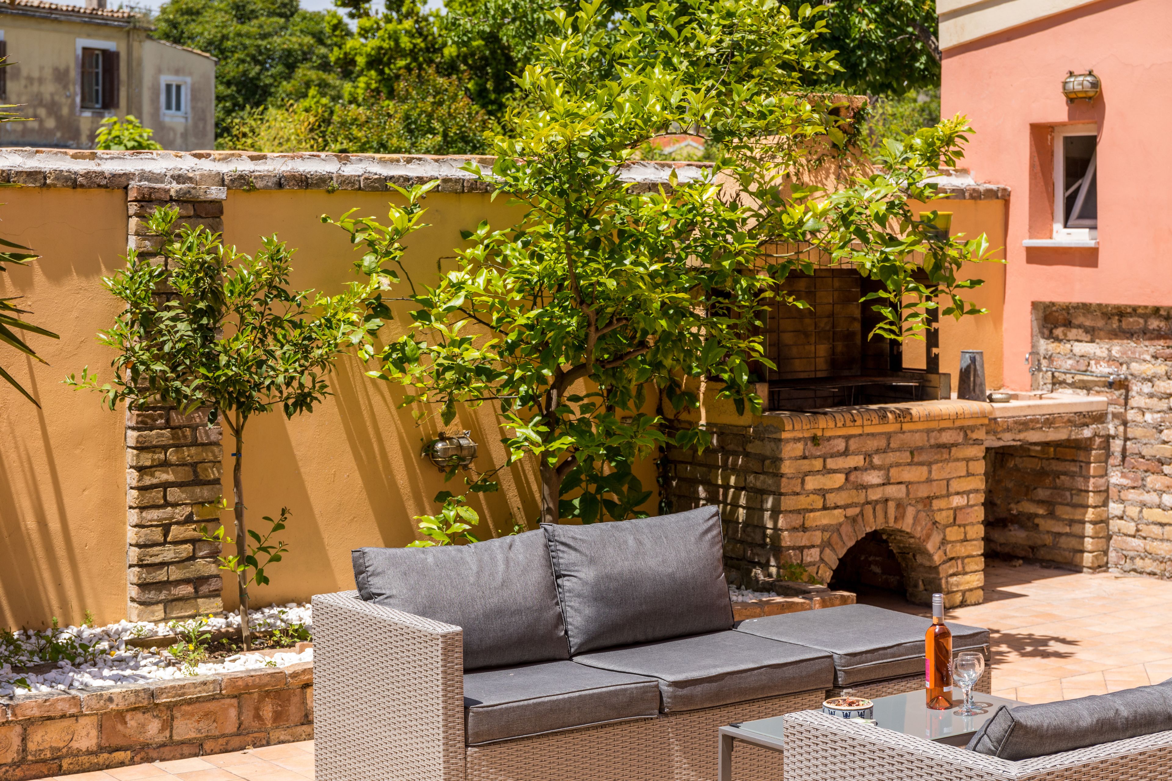 An outdoor seating area with wicker furniture, a stone wall, and a brick oven.