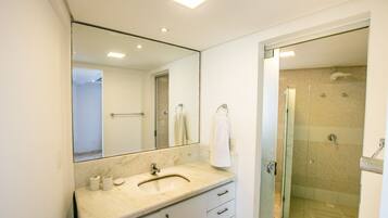 A bathroom with a marble sink, a large mirror, a glass shower enclosure, and a towel rack.
