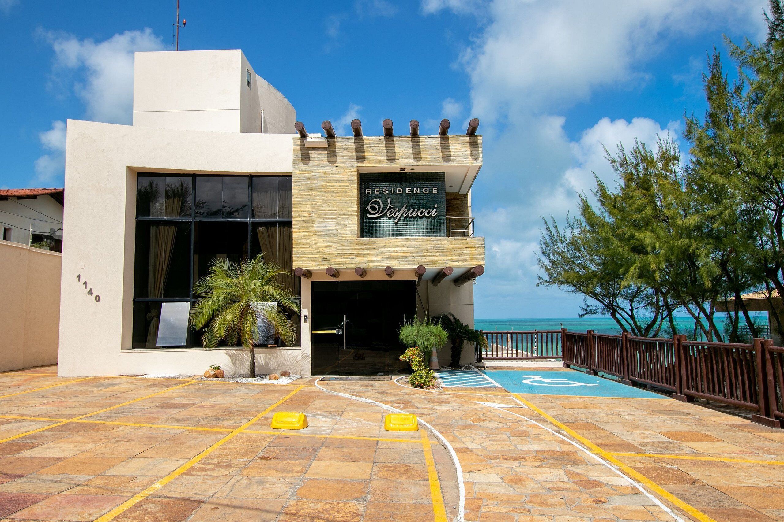 Un edificio moderno con un letrero que dice "Residence Despucci" y una zona de piscina con un camino accesible para sillas de ruedas.