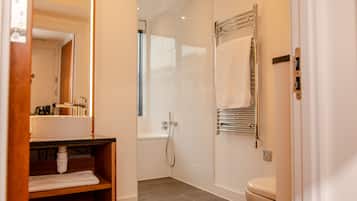 Une salle de bain moderne équipée d’un lavabo, d’un miroir, d’un porte-serviettes, d’une douche et de toilettes.