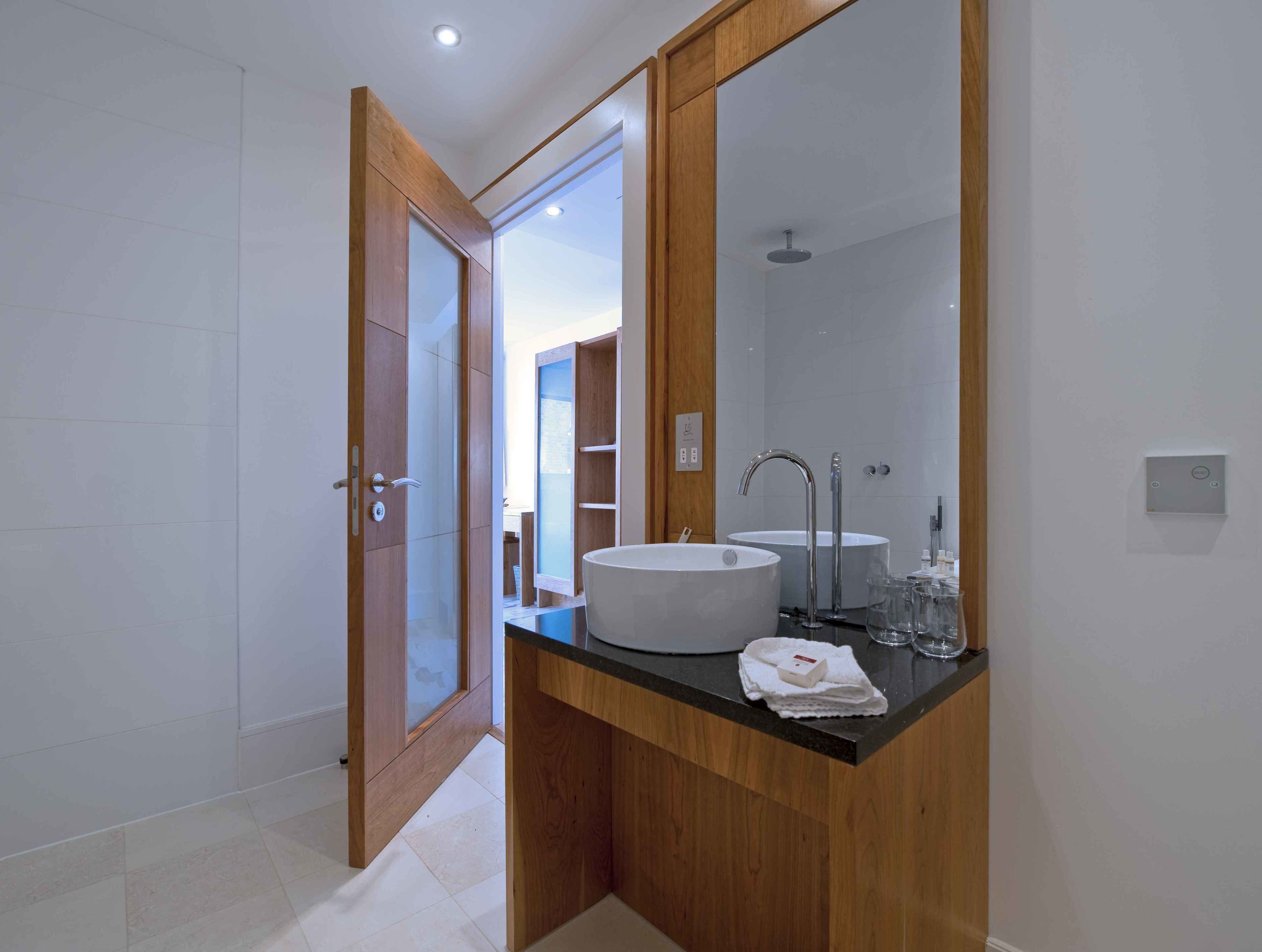 A modern bathroom with a wooden vanity, a large mirror, and a white sink.