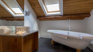 Un baño moderno con tragaluces, una bañera independiente y un tocador de madera.