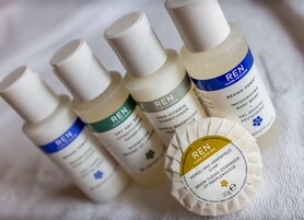 Una selección de productos Ren para el cuidado de la piel, como gel de ducha y champú, sobre una superficie blanca.