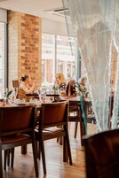 A restaurant with brick walls, wooden tables, and chairs.