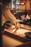 A chef preparing food in a kitchen with a focus on the cooking process.