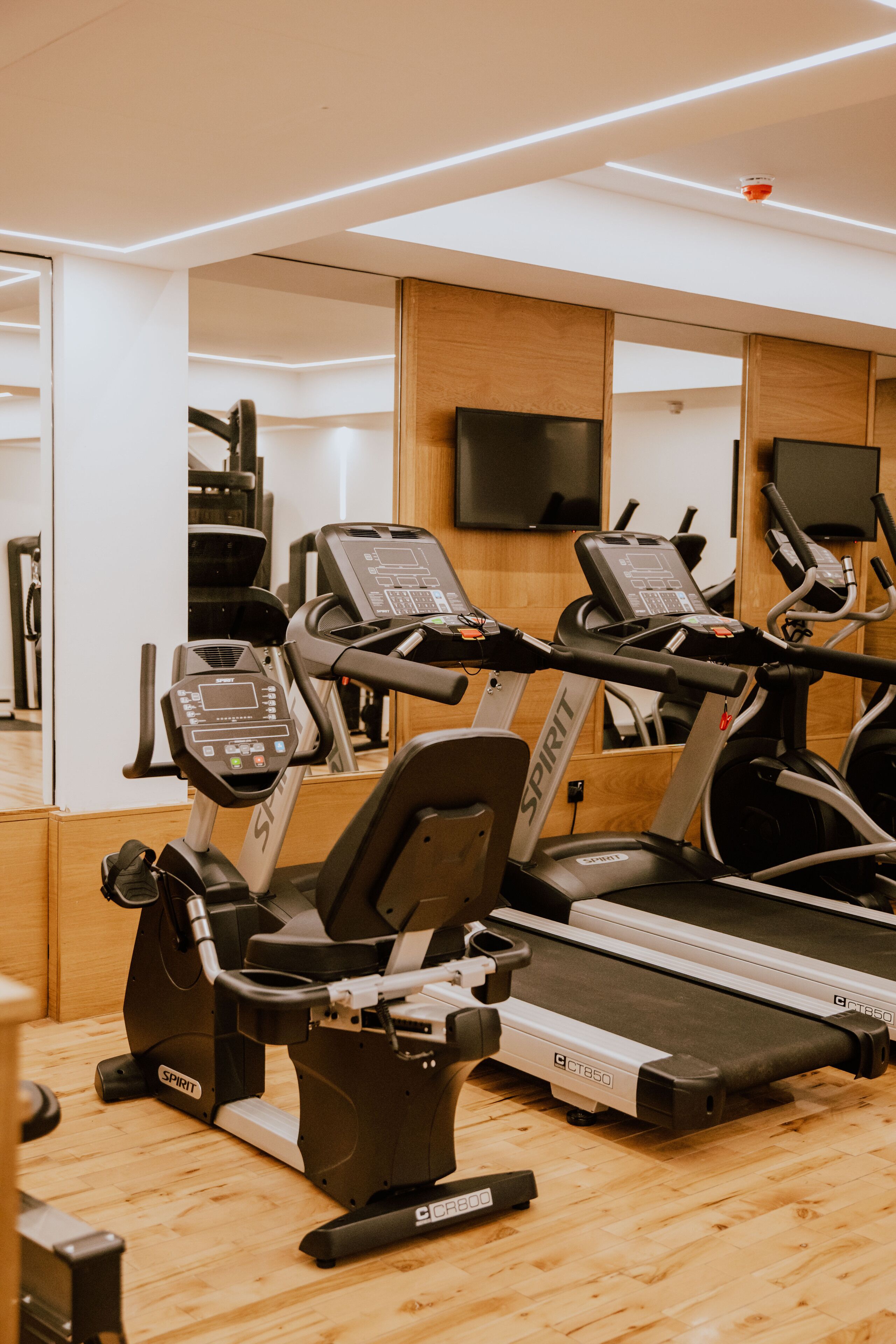 A gym with multiple treadmills, exercise bikes, and a mirrored wall.