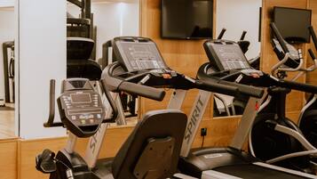 A gym with multiple treadmills, exercise bikes, and a mirrored wall.