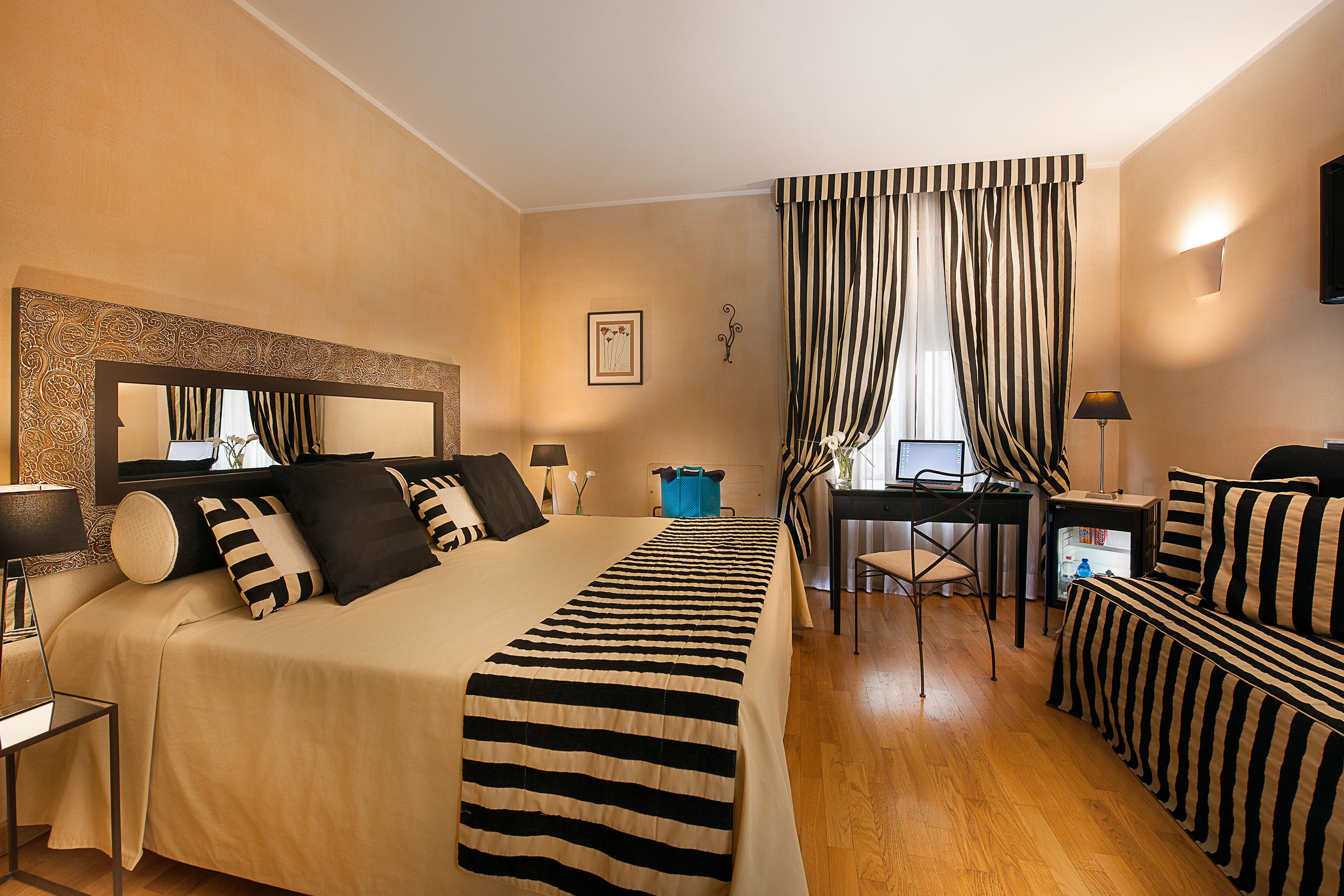 A hotel room with a large bed, a desk, a chair, a TV, and a window with curtains.