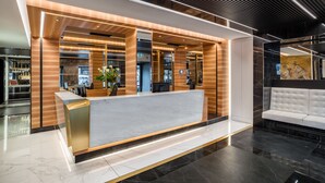 A modern reception desk with a marble top, wooden accents, and a seating area with a white sofa. - Hotel Mastino (Verona)