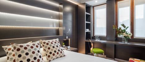 A modern bedroom with a large bed, a desk, and a window with a view.