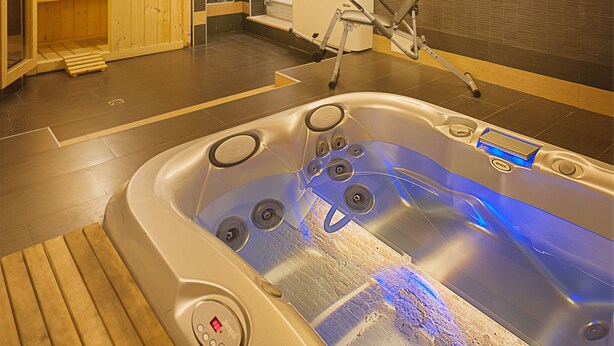 A spa room with a wooden sauna, a massage chair, and a hot tub. - Hotel Mastino (Verona)