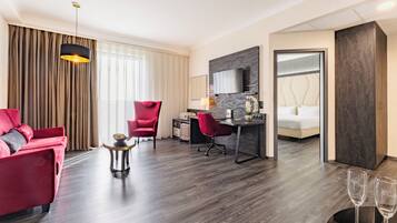 Een moderne hotelkamer met een rode bank, een bureau met stoel, een bed, een televisie en een minibar.