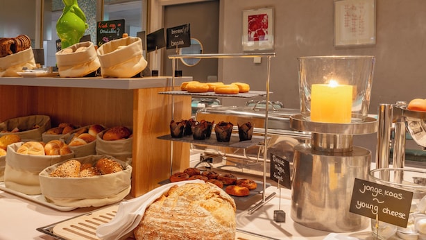 A breakfast buffet with various breads, pastries, and a candle. - PLAZA Premium Grand Winston (Rijswijk)