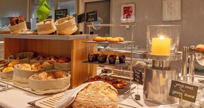 A breakfast buffet with various breads, pastries, and a candle. - PLAZA Premium Grand Winston (Rijswijk)