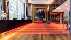 A hotel lobby with a red carpet, a reception desk, a large portrait, and a staircase. - PLAZA Premium Grand Winston (Rijswijk)