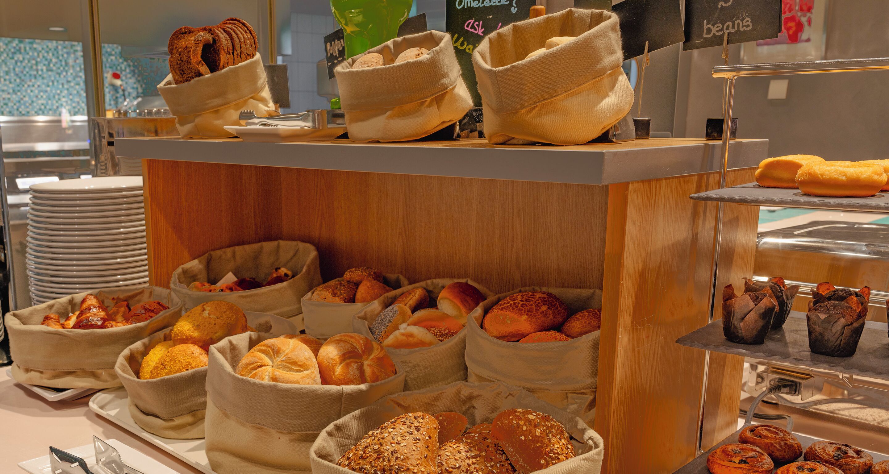 A bakery display with various breads and pastries in woven baskets.