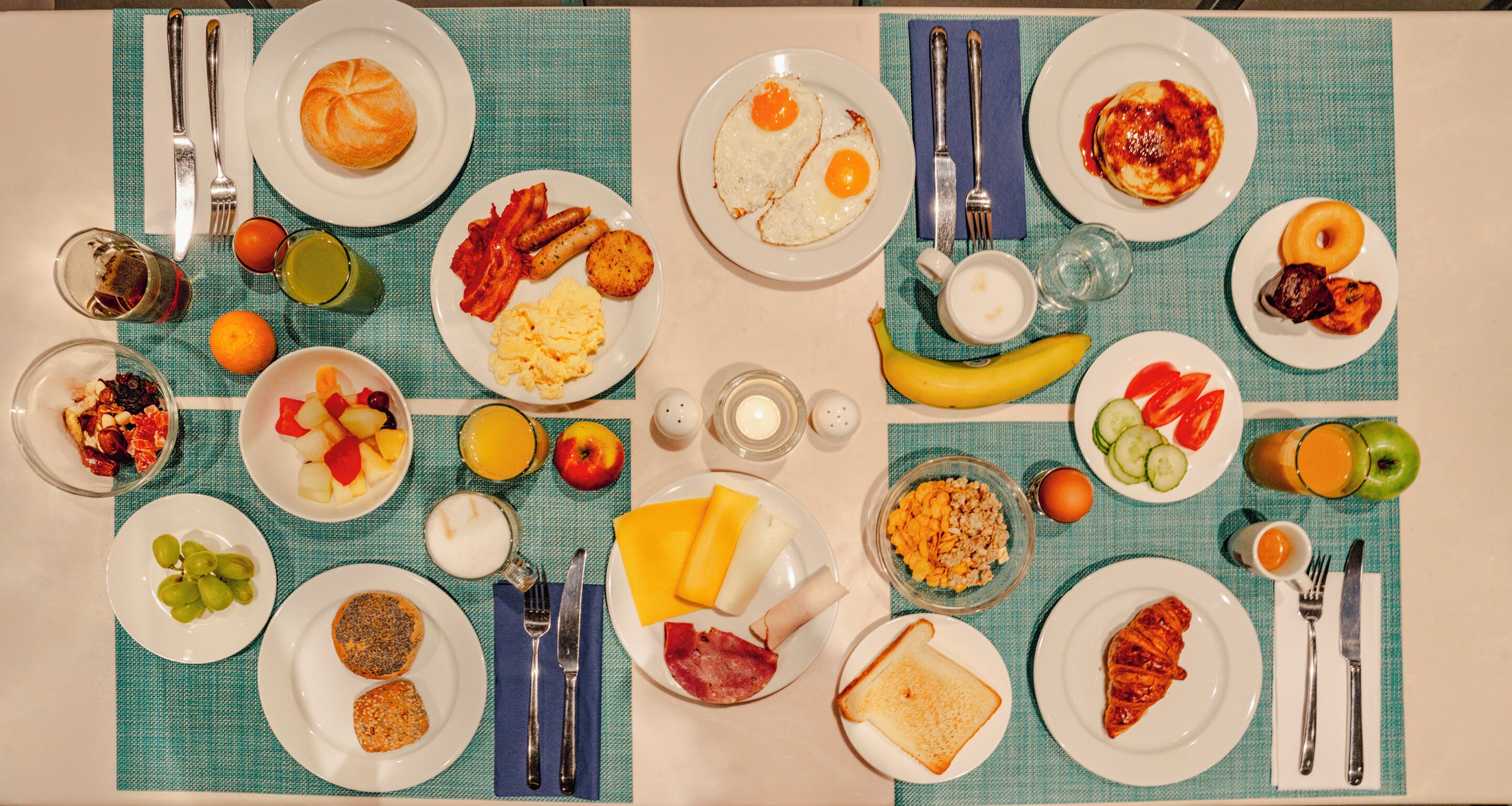 Un ricco buffet per la colazione con diversi cibi e utensili disposti su un tavolo.