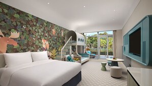 Una habitación de hotel moderna con una cama grande, una zona de juegos para niños, un balcón con vistas y un televisor.