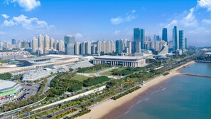A coastal cityscape with modern skyscrapers, a large central building, and a beach.