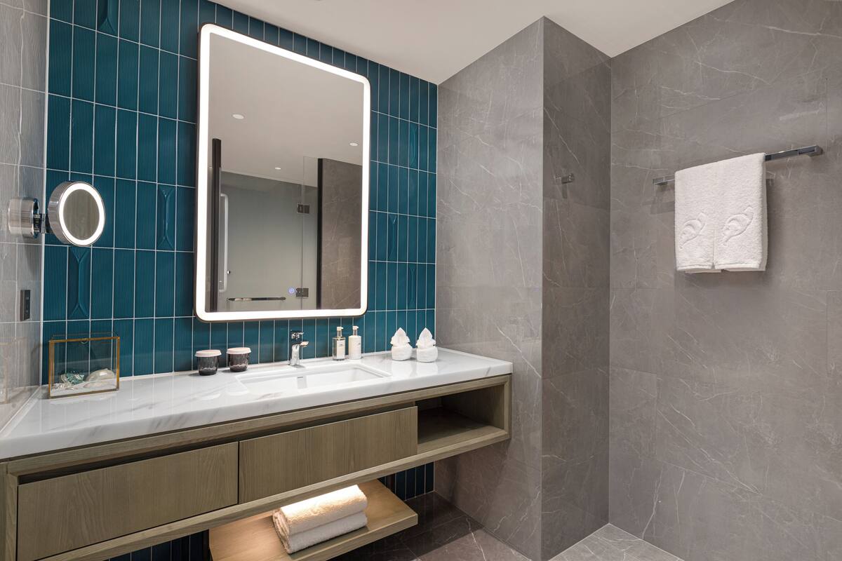 Een moderne badkamer met een grote spiegel, een wastafel en een douchehoek.
