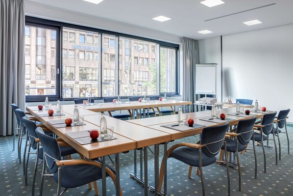 A conference room with long tables, chairs, and a whiteboard.