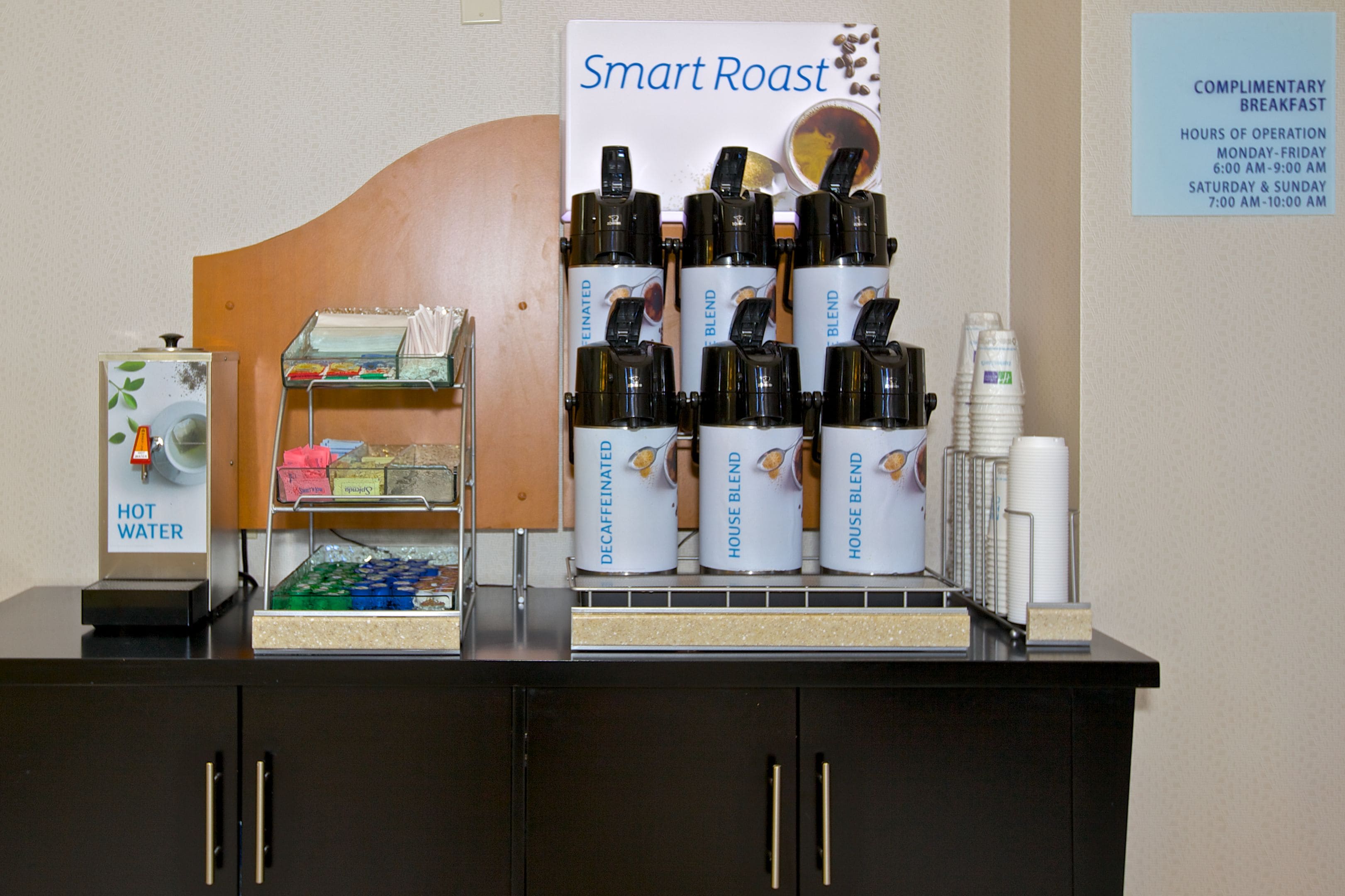 A coffee station with a sign reading "Smart Roast" and a sign listing complimentary breakfast hours.