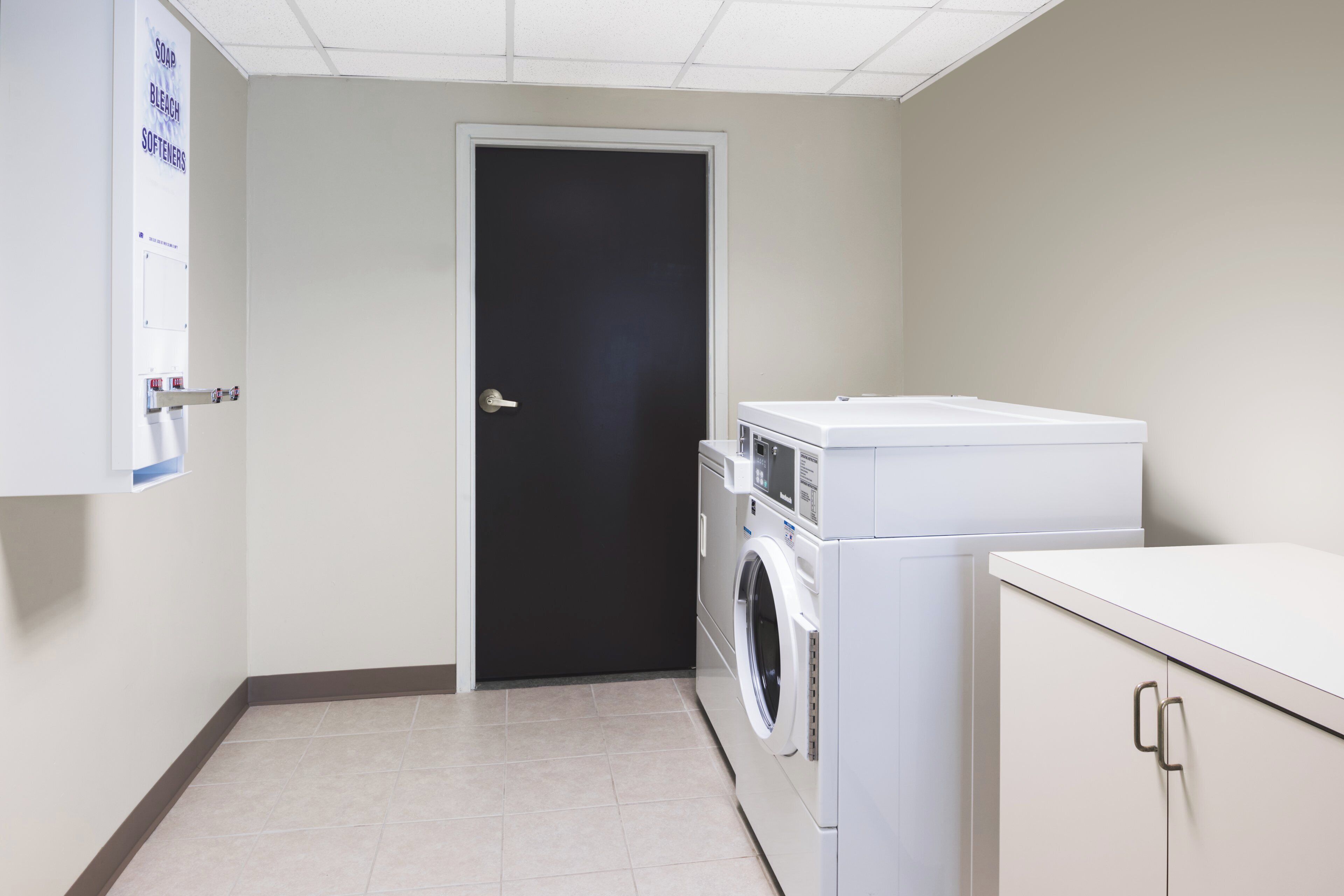Un cuarto de lavado con una puerta, una lavadora y una secadora.