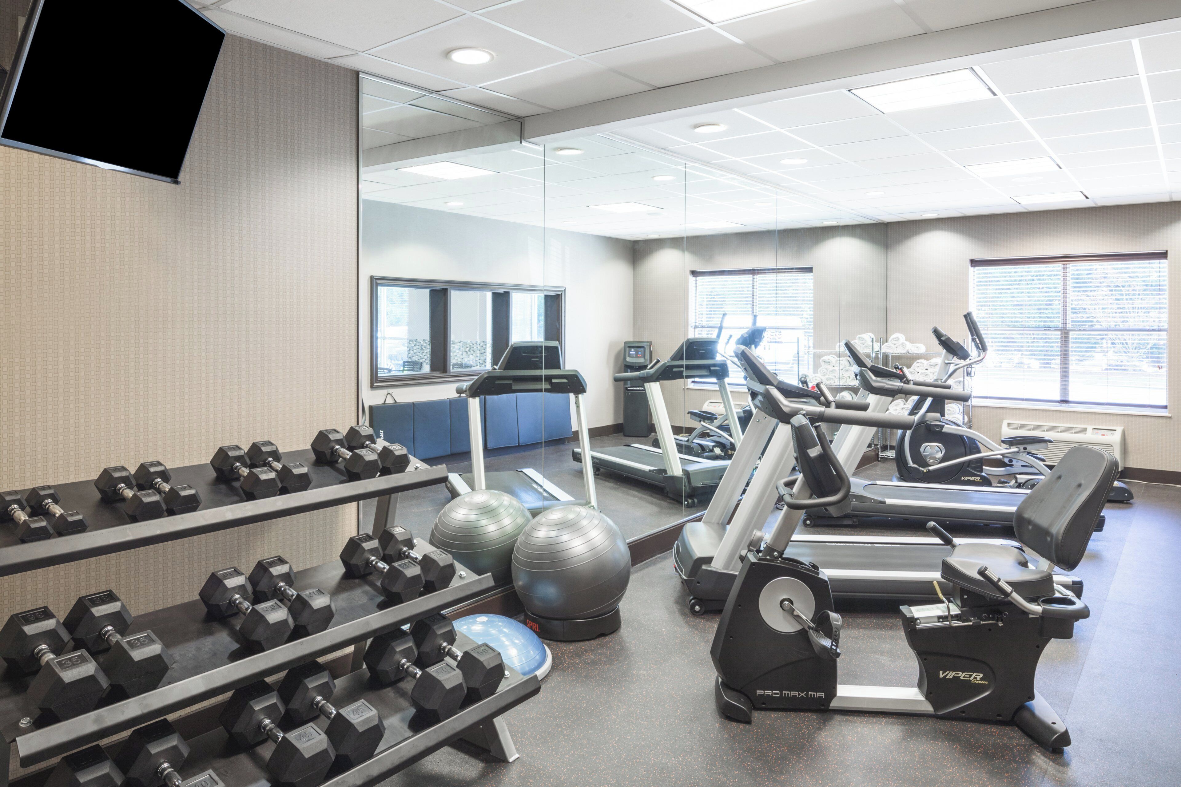 A gym with exercise equipment, including treadmills and dumbbells.
