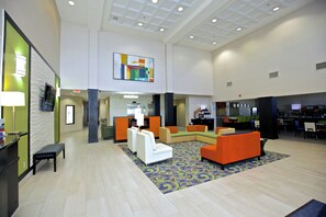 A spacious lobby with a high ceiling, a reception desk, seating area with sofas, and a patterned carpet. - Holiday Inn Express & Suites Atlanta NE - Duluth by IHG (Duluth)