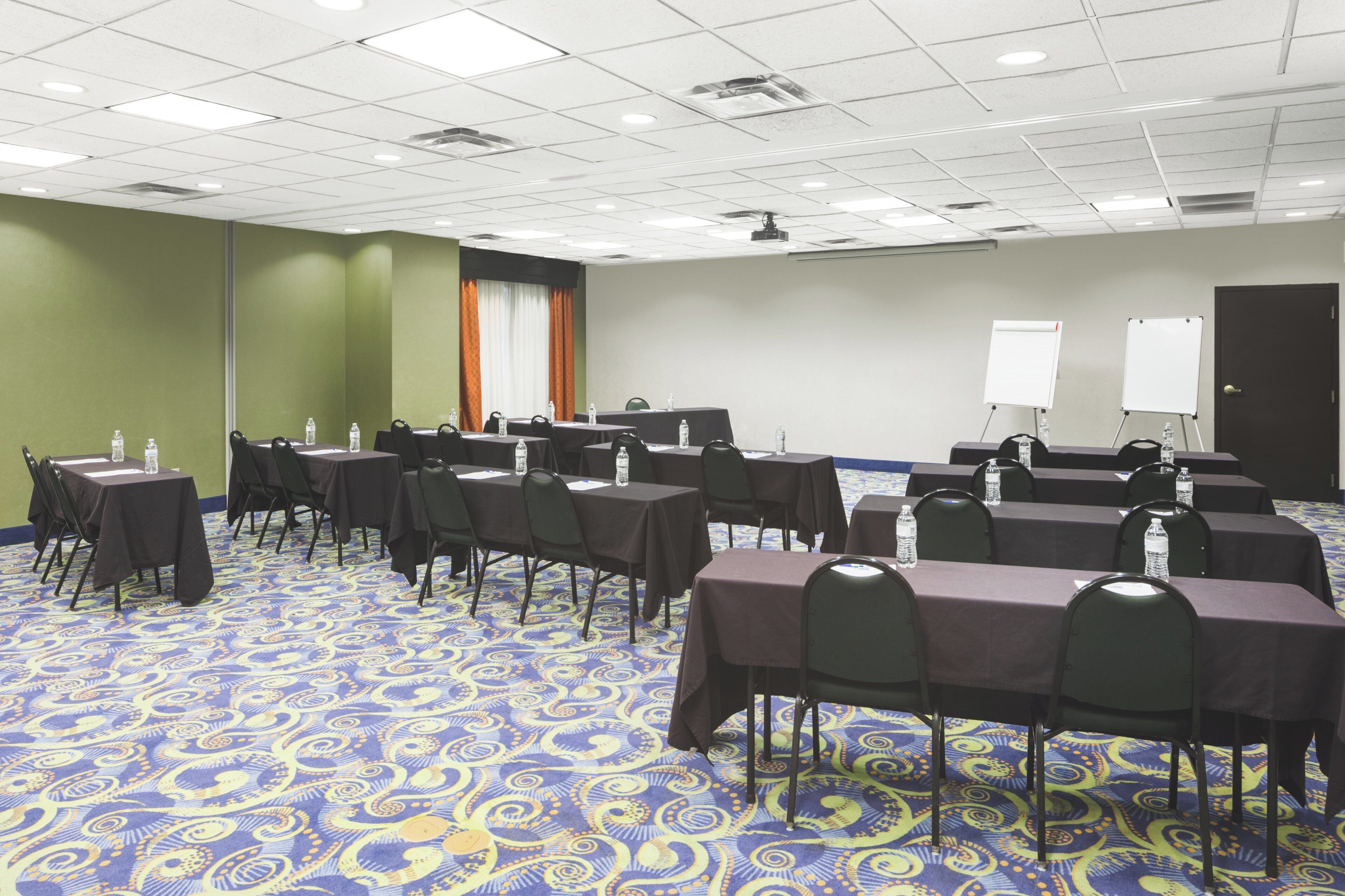 Une salle de conférence équipée de tables, de chaises et d’un écran de projection.