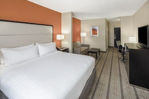 A hotel room with a large bed, a desk, a chair, a TV, and a lamp. - Holiday Inn Express & Suites Atlanta NE - Duluth by IHG (Duluth)