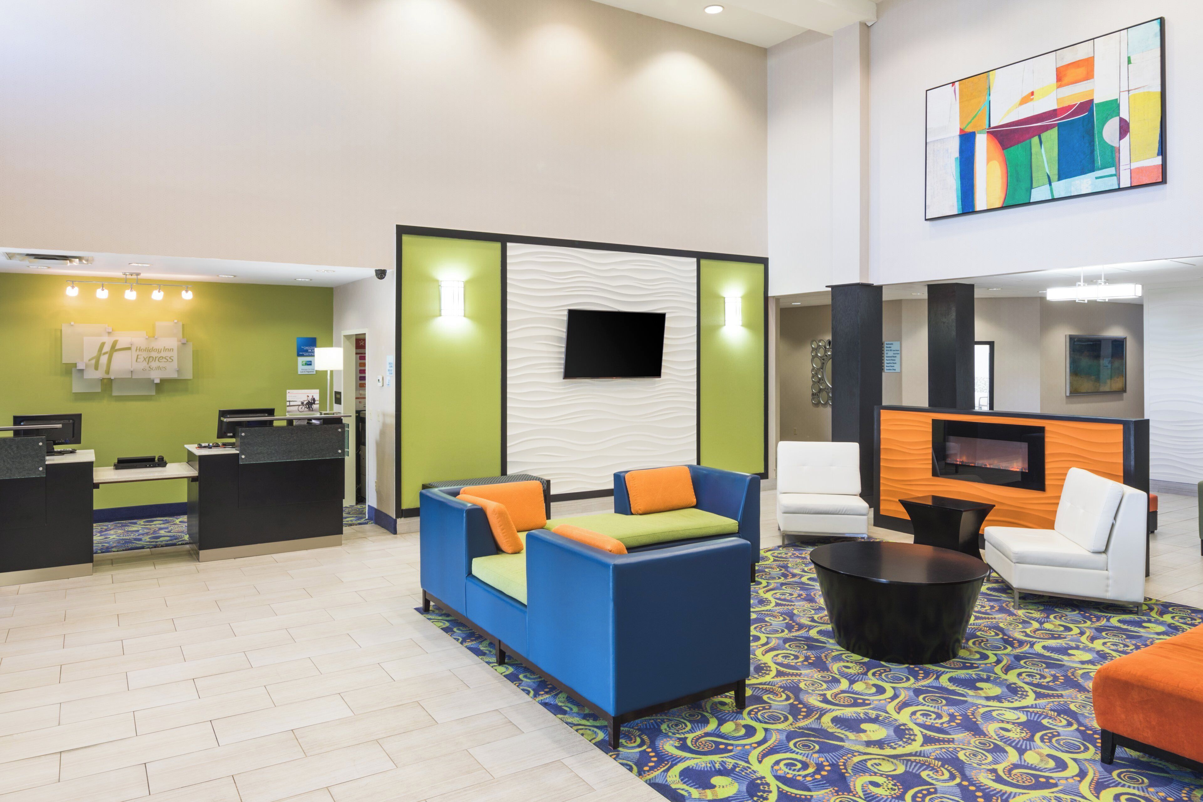 A hotel lobby with a reception desk, seating area, and a television screen.