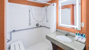 Ein modernes Badezimmer mit Dusche, Haltegriff, Waschbecken und Spiegel.