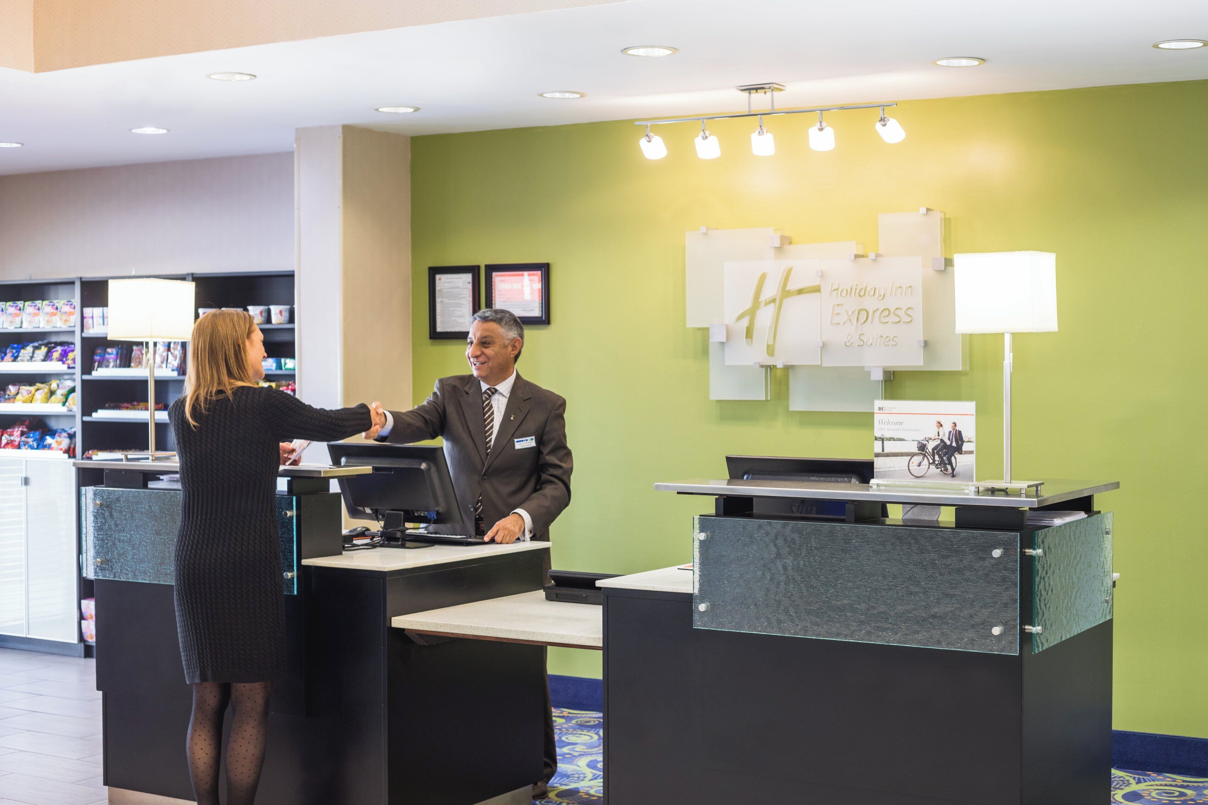 A hotel reception desk with a man and a woman shaking hands.
