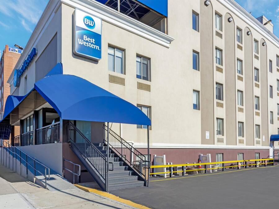 Ett Best Western-hotell med ett blått markis, en trappa som leder upp till entrén och en parkeringsplats med gula säkerhetsmarkeringar.