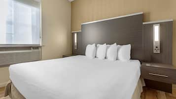 Ein modernes Hotelzimmer mit einem großen Bett, einem Nachttisch, einer Wandlampe und einer Nachttischlampe.