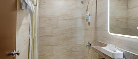 A bathroom with a shower, toilet, sink, and a mirror.
