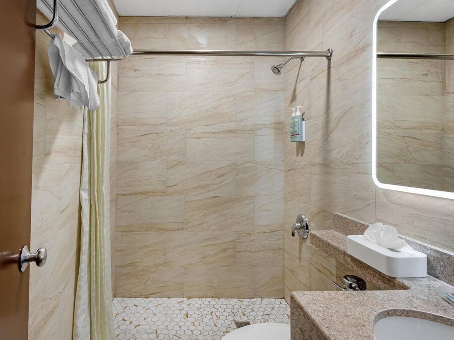 Un baño con ducha, inodoro, lavabo y espejo.