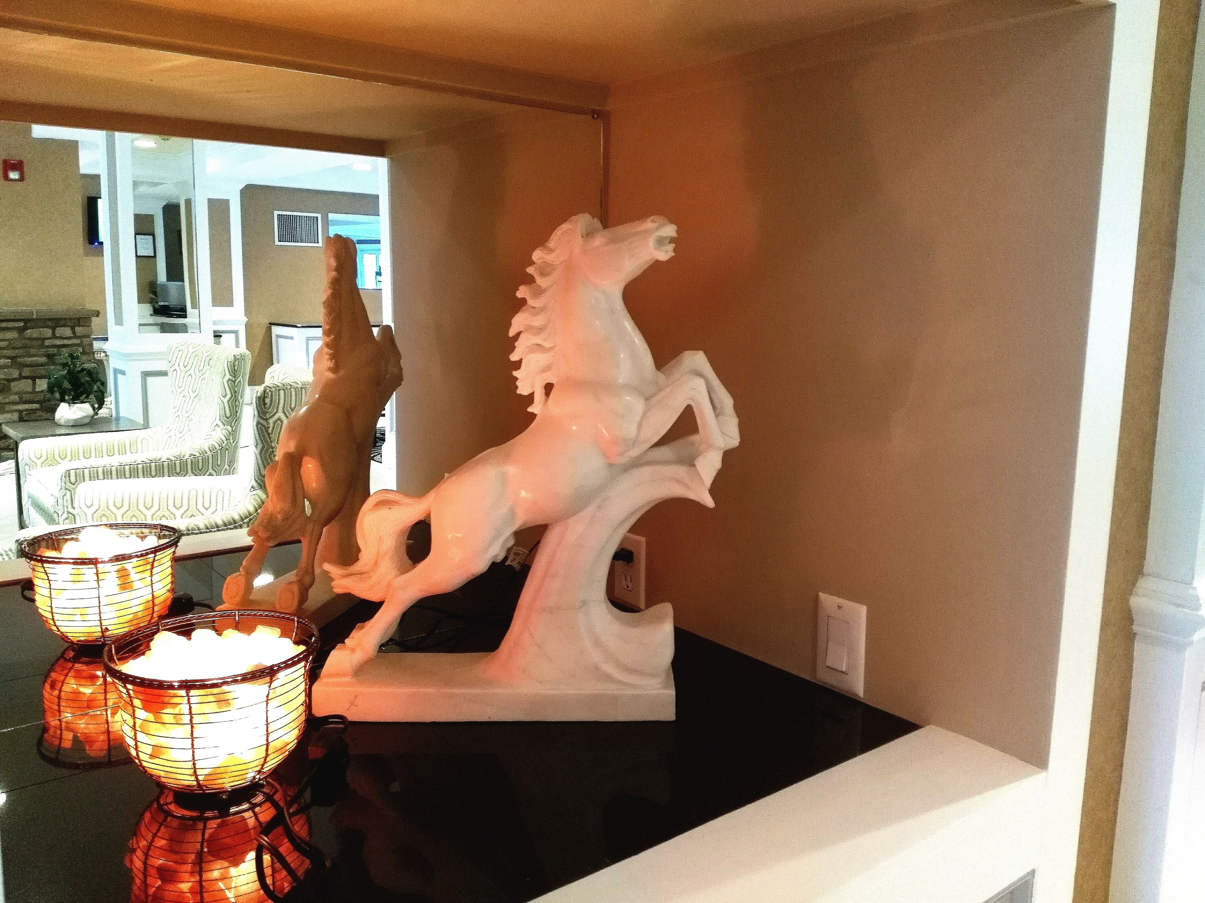 Una habitación con una encimera negra, una escultura de un caballo blanco y dos velas encendidas.