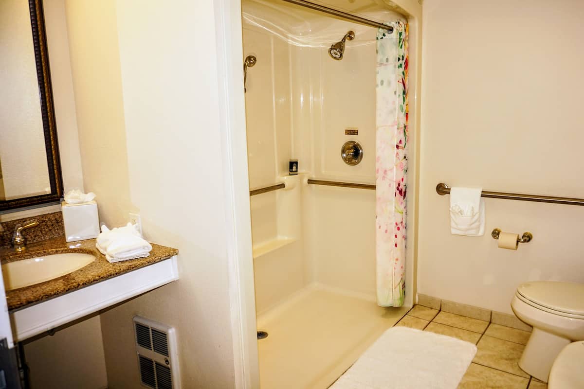 A bathroom with a shower, toilet, sink, and towel rack.