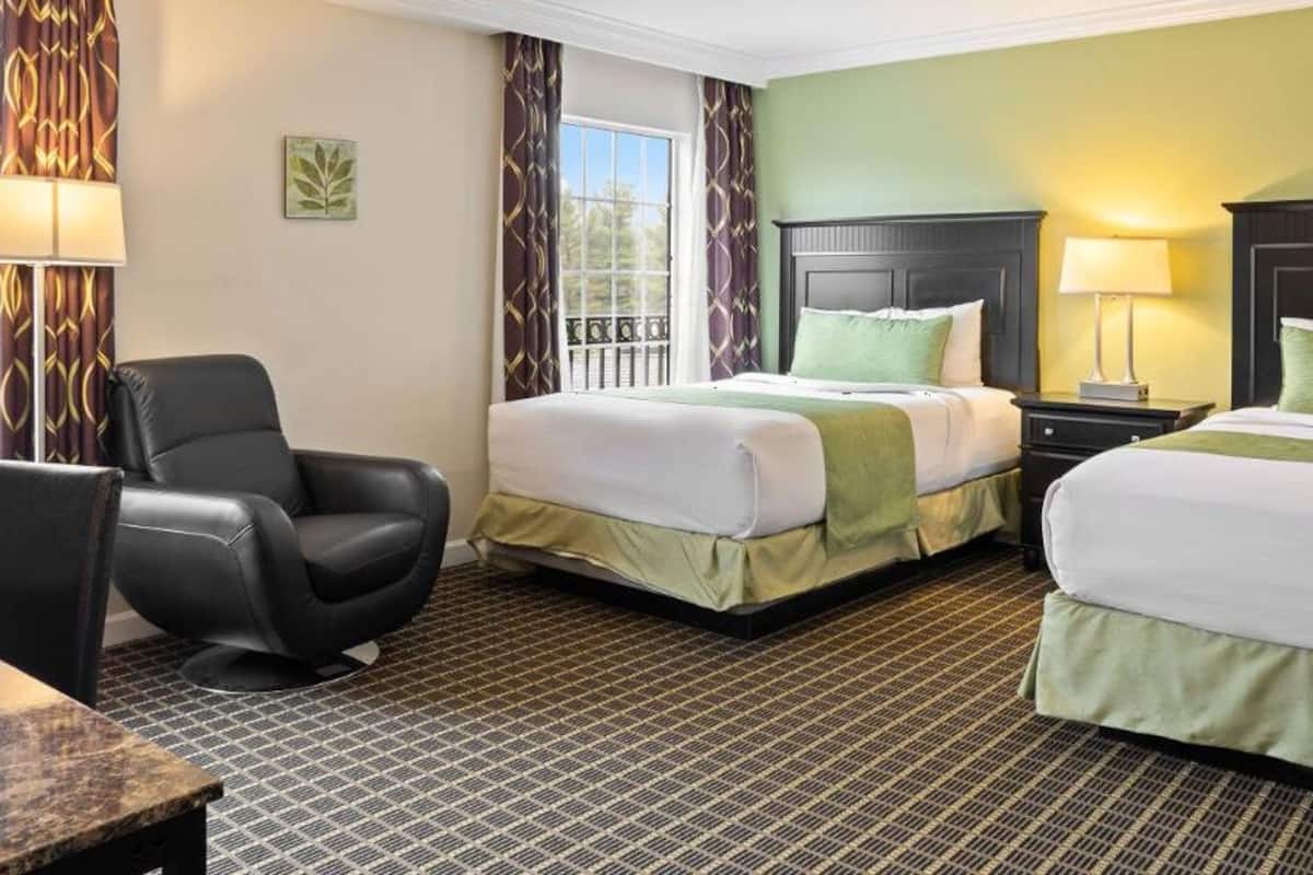 A hotel room with two beds, a desk, and a chair.