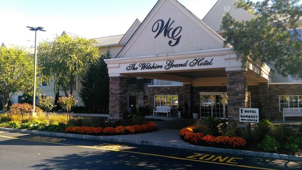 The Wilderness Grand Hotel with a stone facade, a sign indicating a banquet center, and a 'ZONE' marking on the road. - The Wilshire Grand Hotel (West Orange)