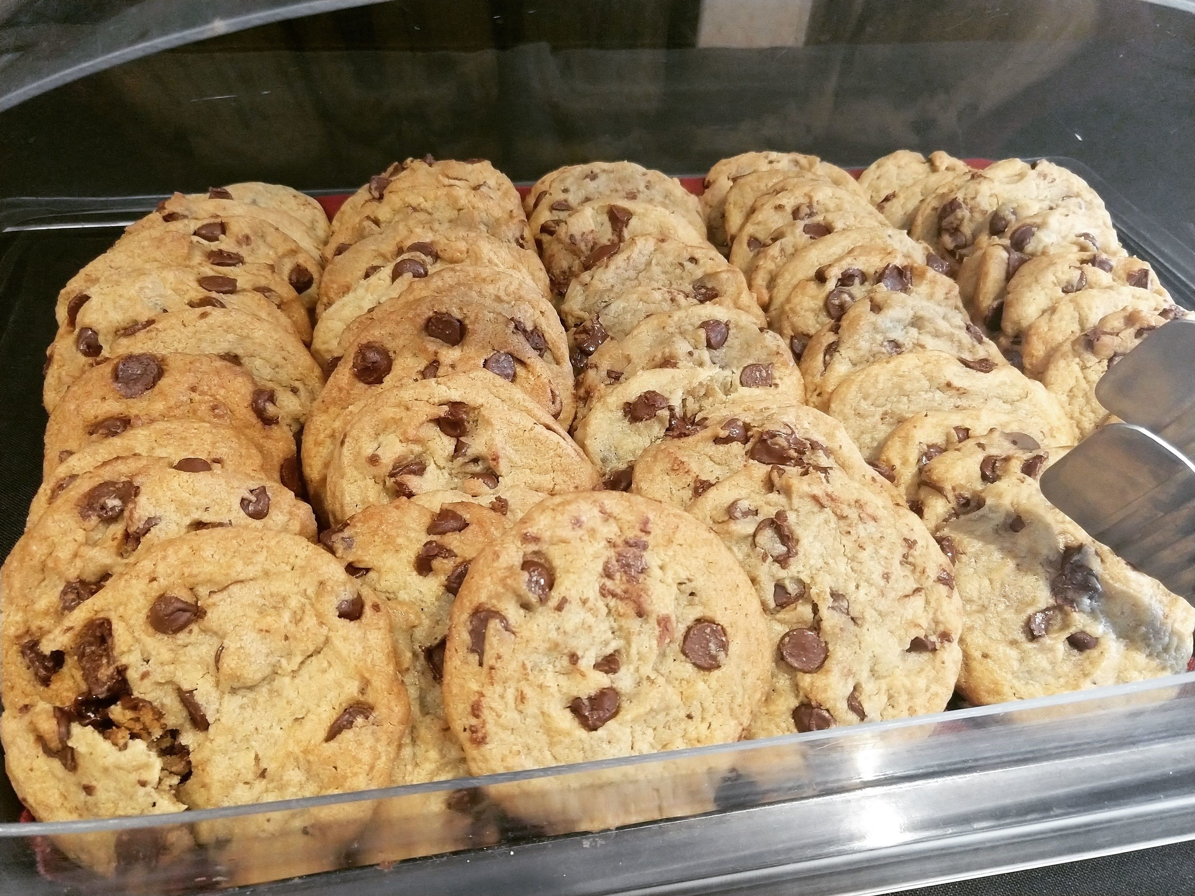 A clear plastic container filled with chocolate chip cookies.