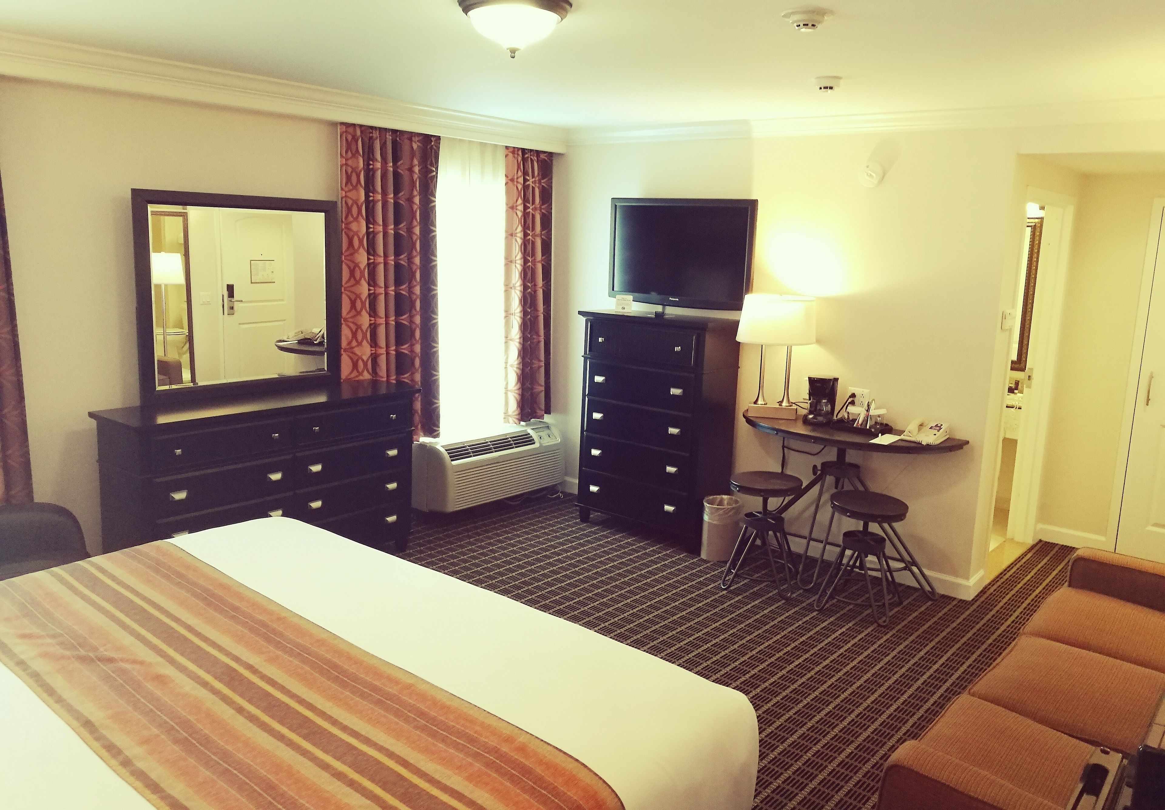 Habitación de hotel con una cama grande, un televisor de pantalla plana, un escritorio con lámpara y una silla.