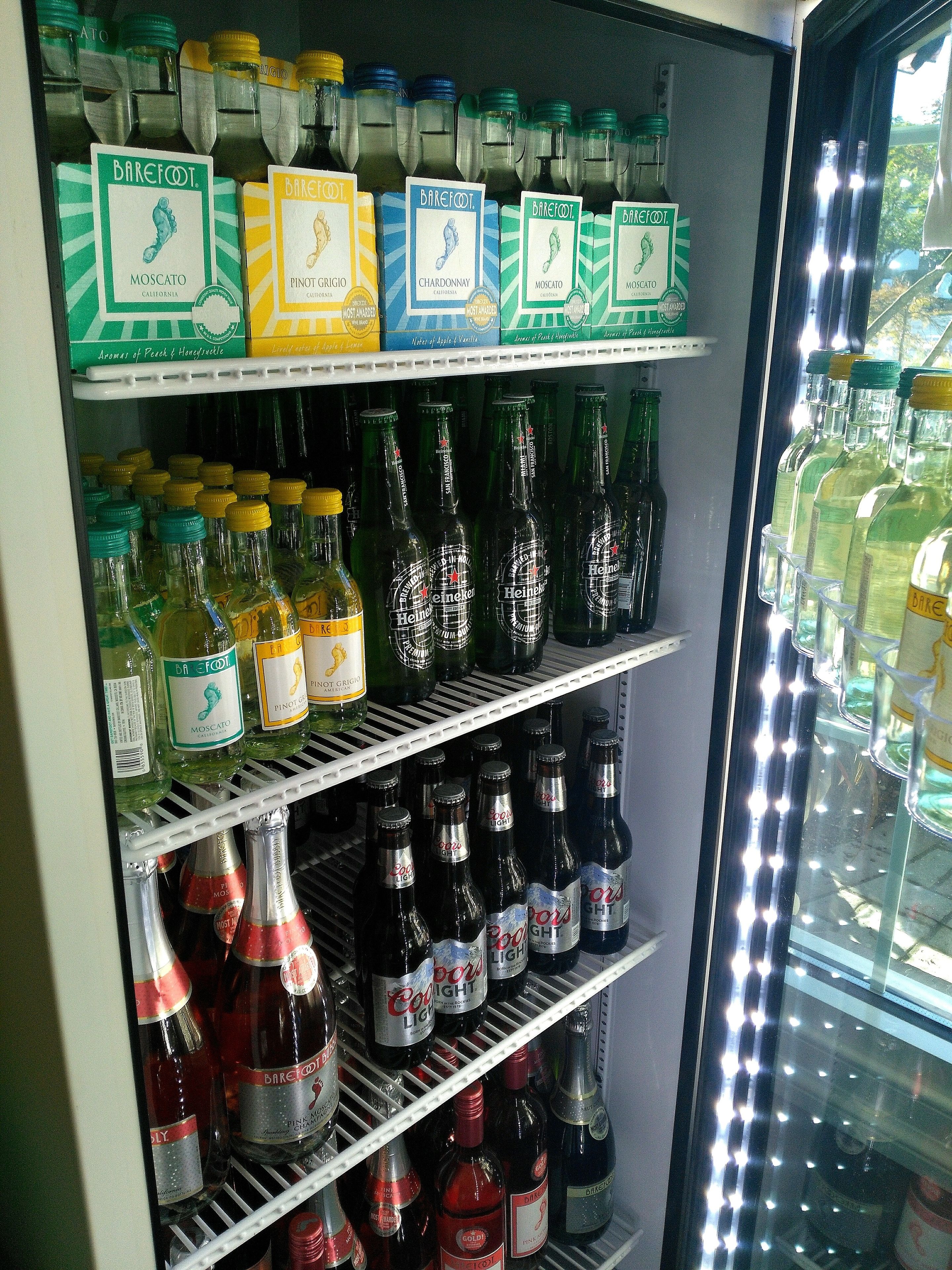 Vitrina refrigerada con diversas botellas de vino y cerveza, incluyendo marcas como Barefoot y Heineken.